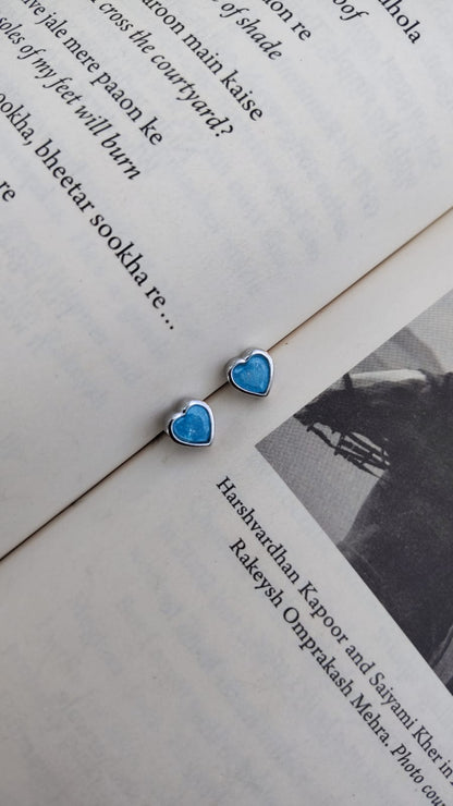 Turquoise heart-shaped 92.5 silver earrings on an open book