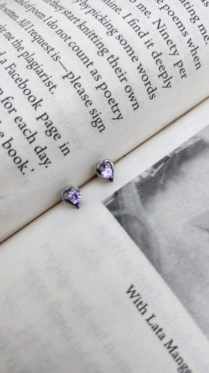 Heart-shaped 92.5 silver earrings with purple stones on an open book