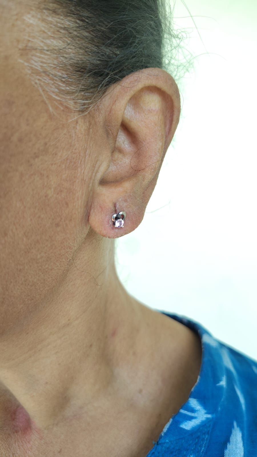 Close-up of a person's ear with a small earring on a blurred background