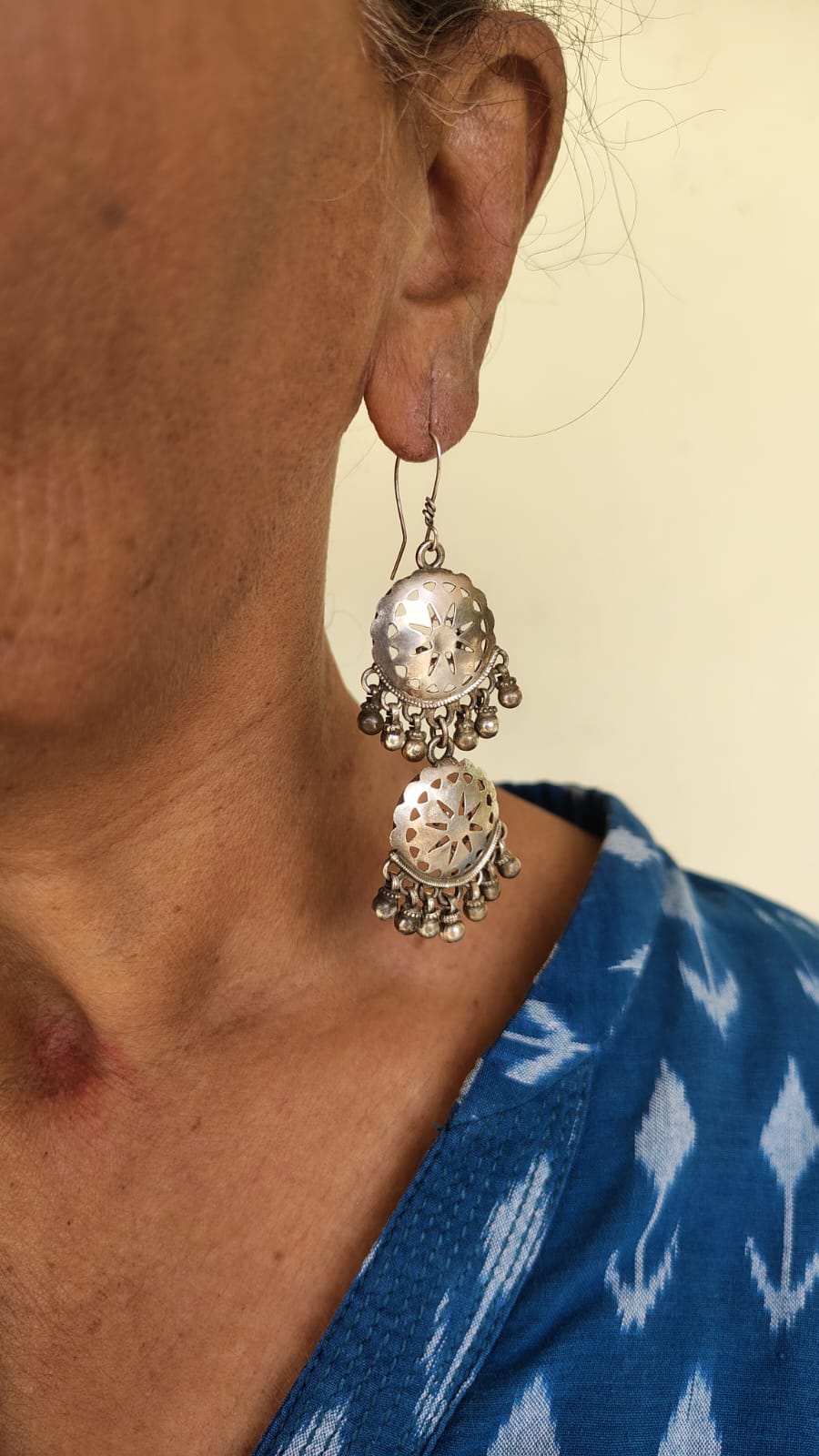Close-up of a person wearing a silver earring with a blue garment in the background