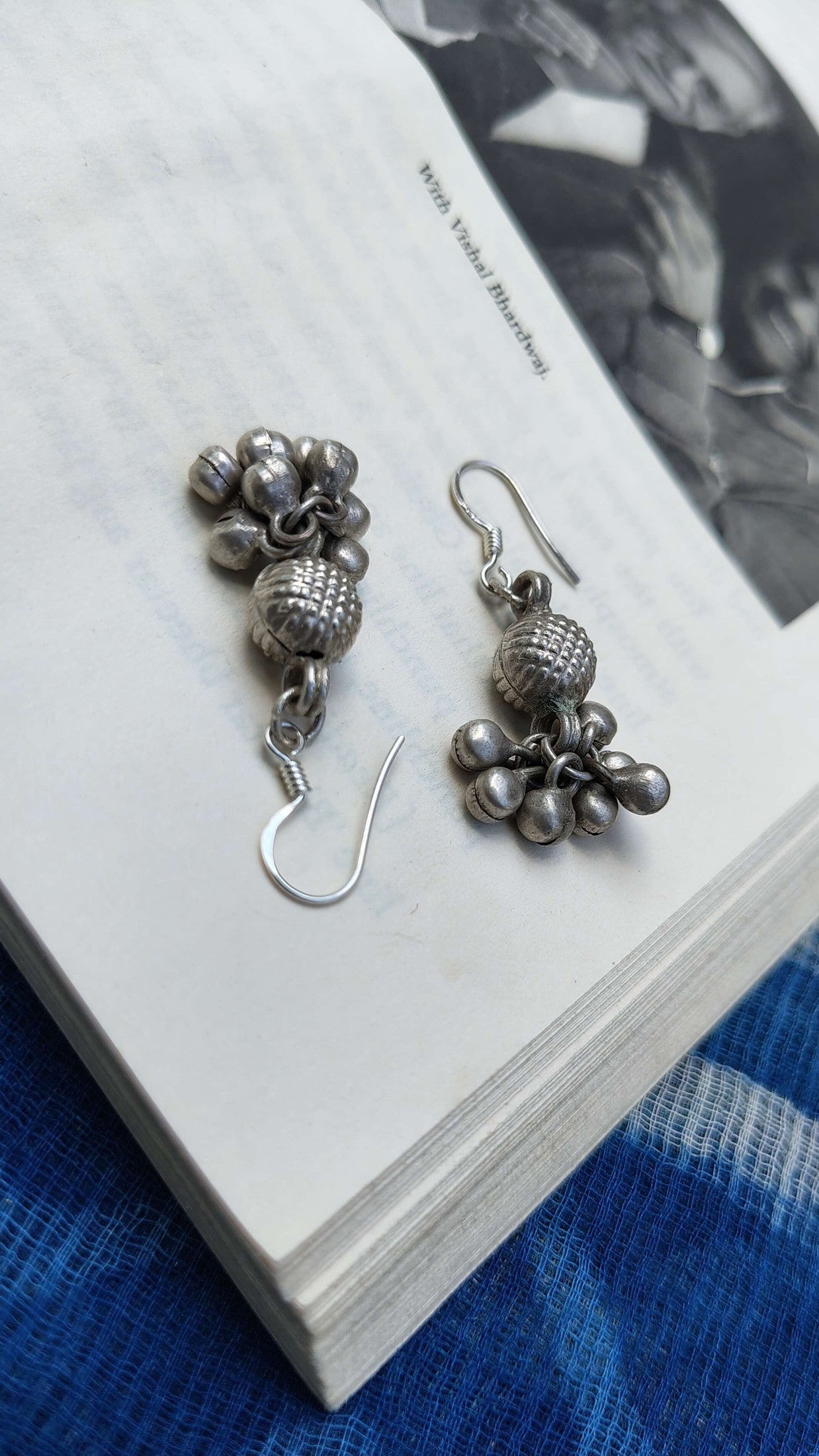 Pair of silver beaded earrings on a book with a blurred background