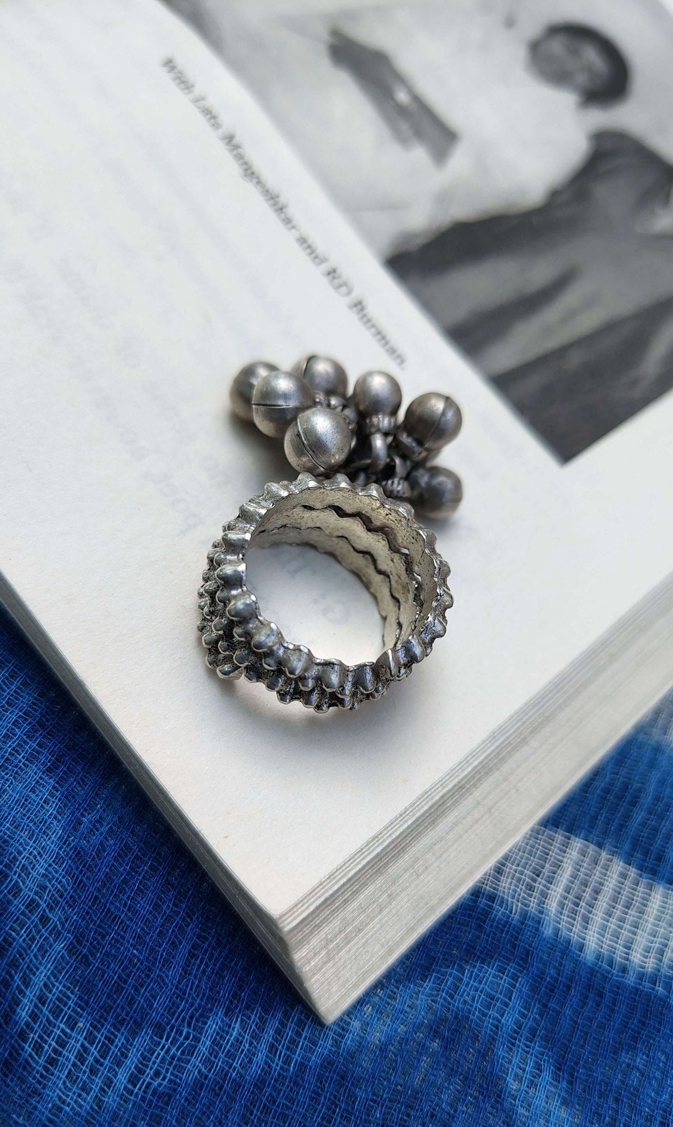 Silver ring with ghungroo on a book