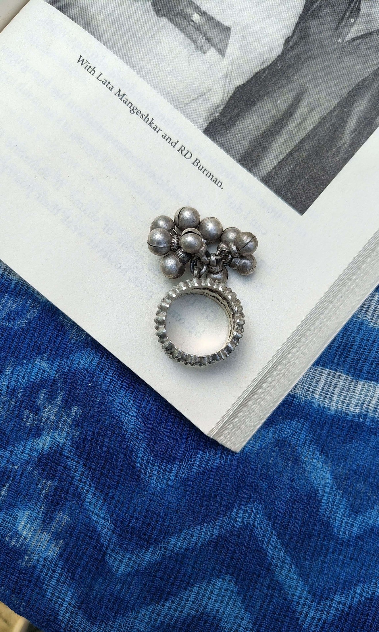 Decorative ring with pearl-like beads on a book with a blue fabric background