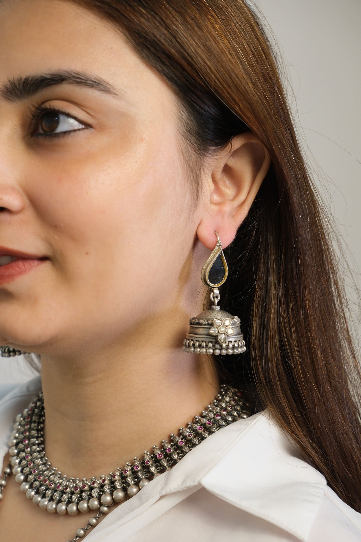 Close-up of a person wearing silver earrings with a blurred background