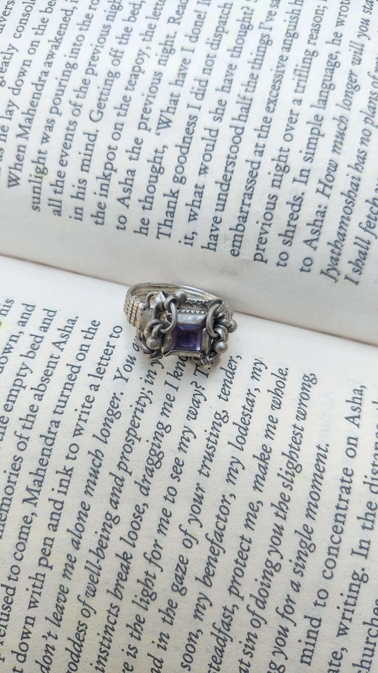 Silver vintage ring with a purple gemstone on an open book - top view | Sadabahaar Jewelry