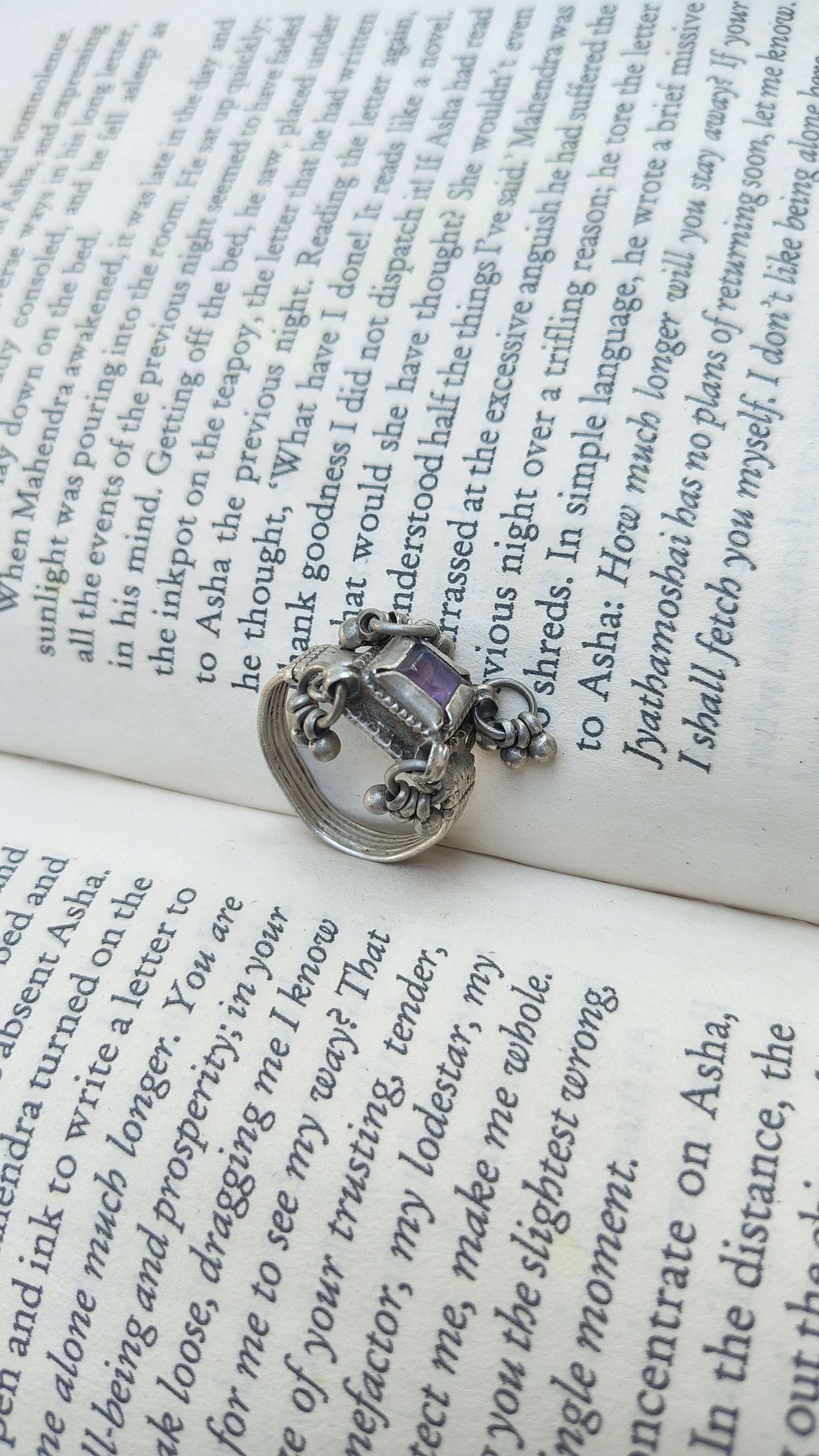 Silver ring with a purple gemstone on an open book