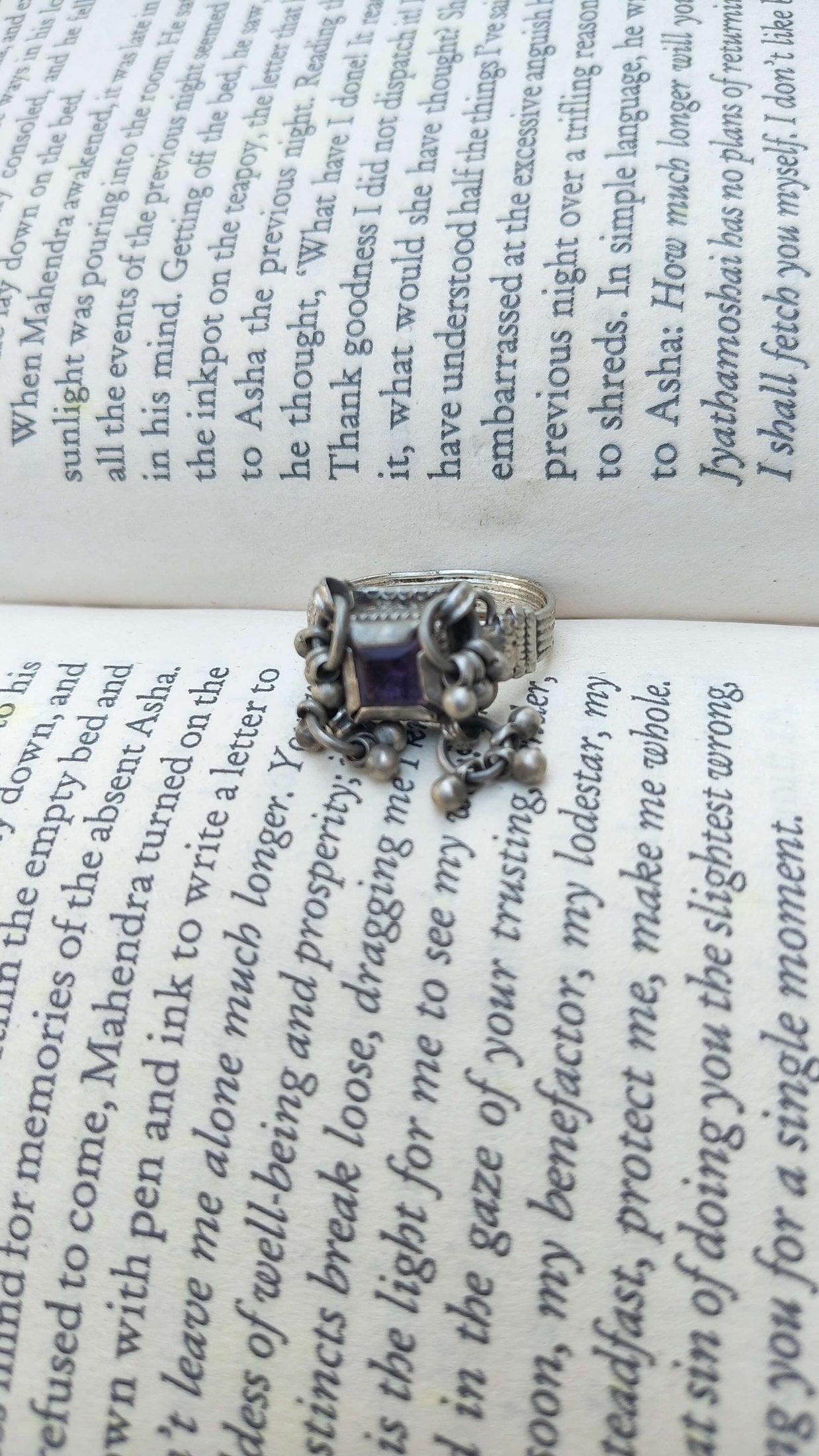 Silver ring with a purple gemstone on an open book | Sadabahaar Jewelry