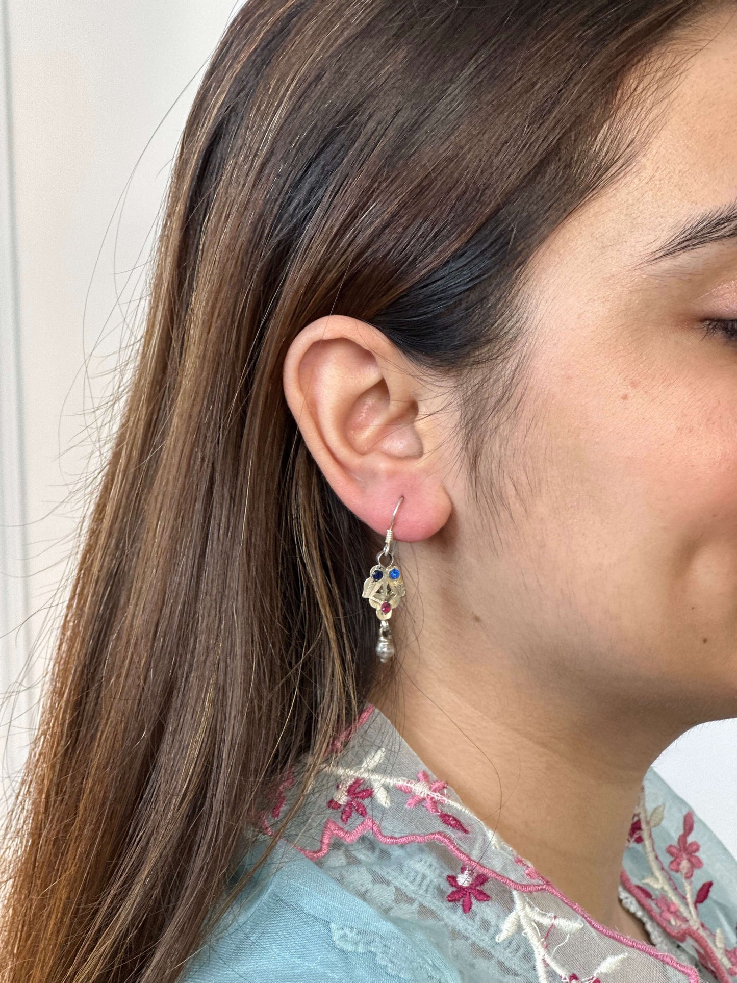 Close-up of a person wearing a floral earring with a light-colored background