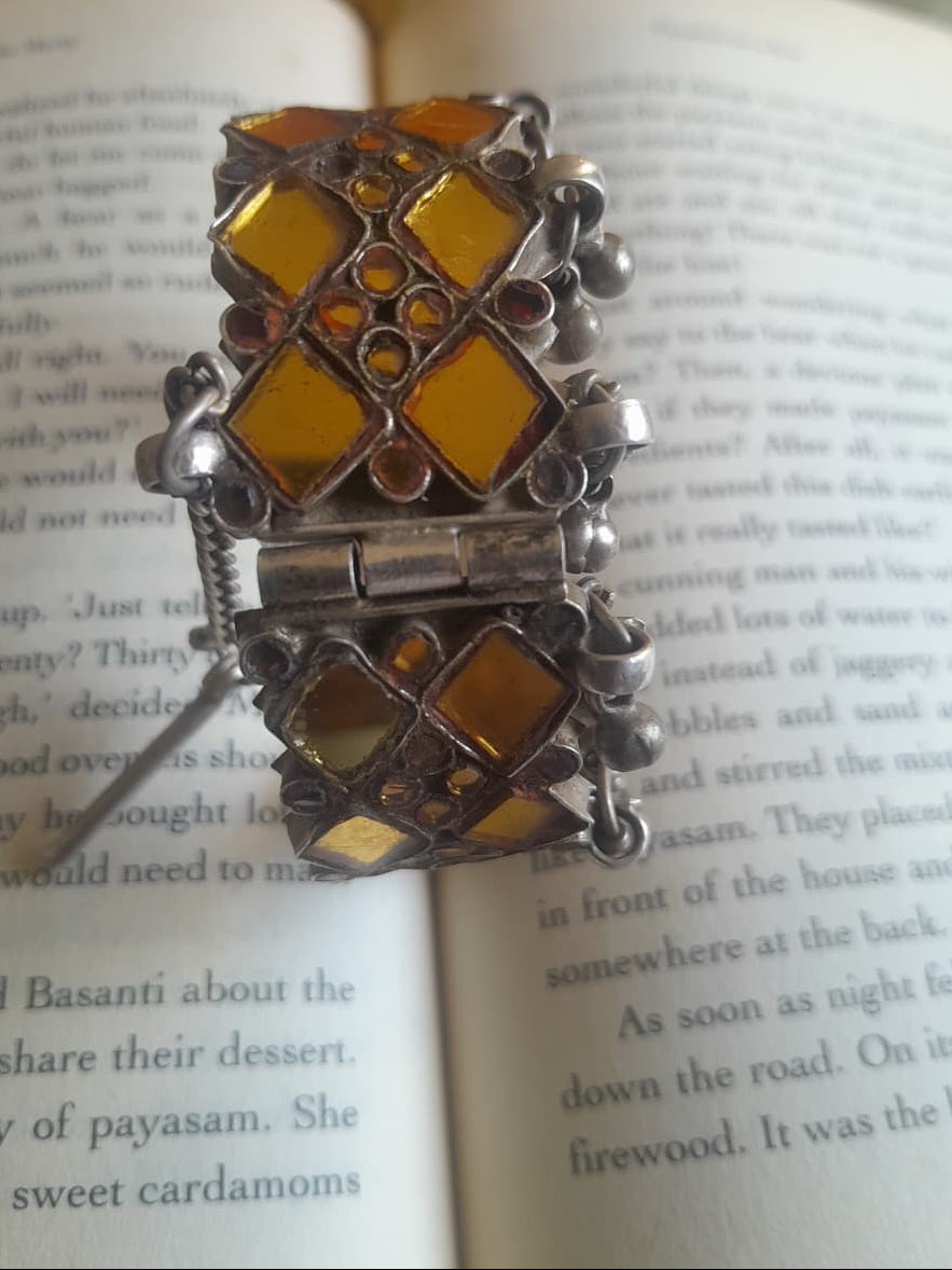 A vintage silver katesari kada in size 2.4 — two rows of yellow kite-shaped glass with yellow glass floral motifs between, ghungroo clusters at the base, and a chain-pull hinge opening.