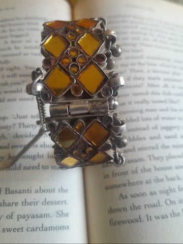 A vintage silver katesari kada in size 2.4 — two rows of yellow kite-shaped glass with yellow glass floral motifs between, ghungroo clusters at the base, and a chain-pull hinge opening.