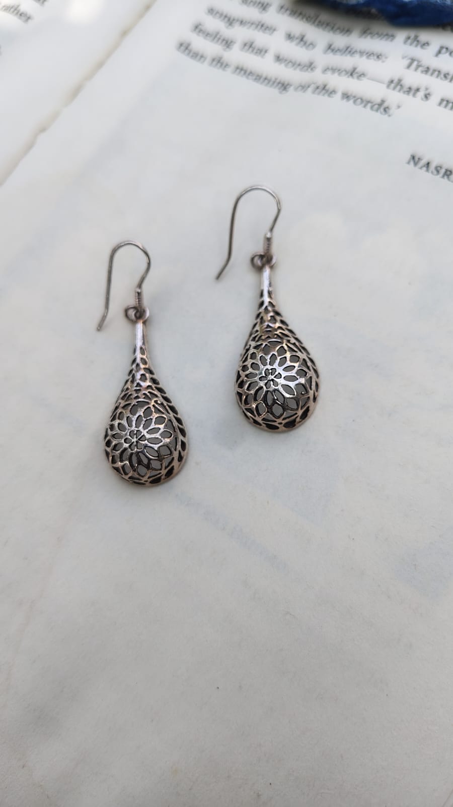 Silver teardrop earrings on a book page