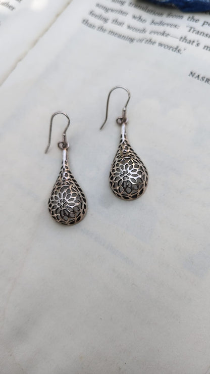 Silver teardrop earrings on a book page