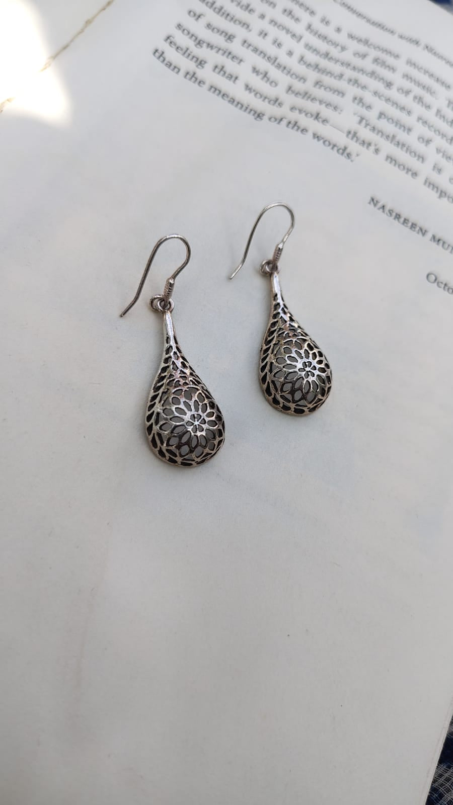 Silver floral-patterned earrings on a white surface