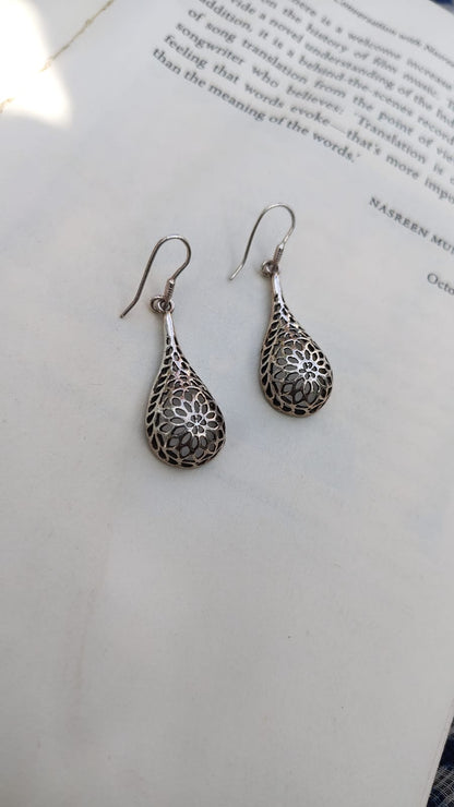 Silver floral-patterned earrings on a white surface