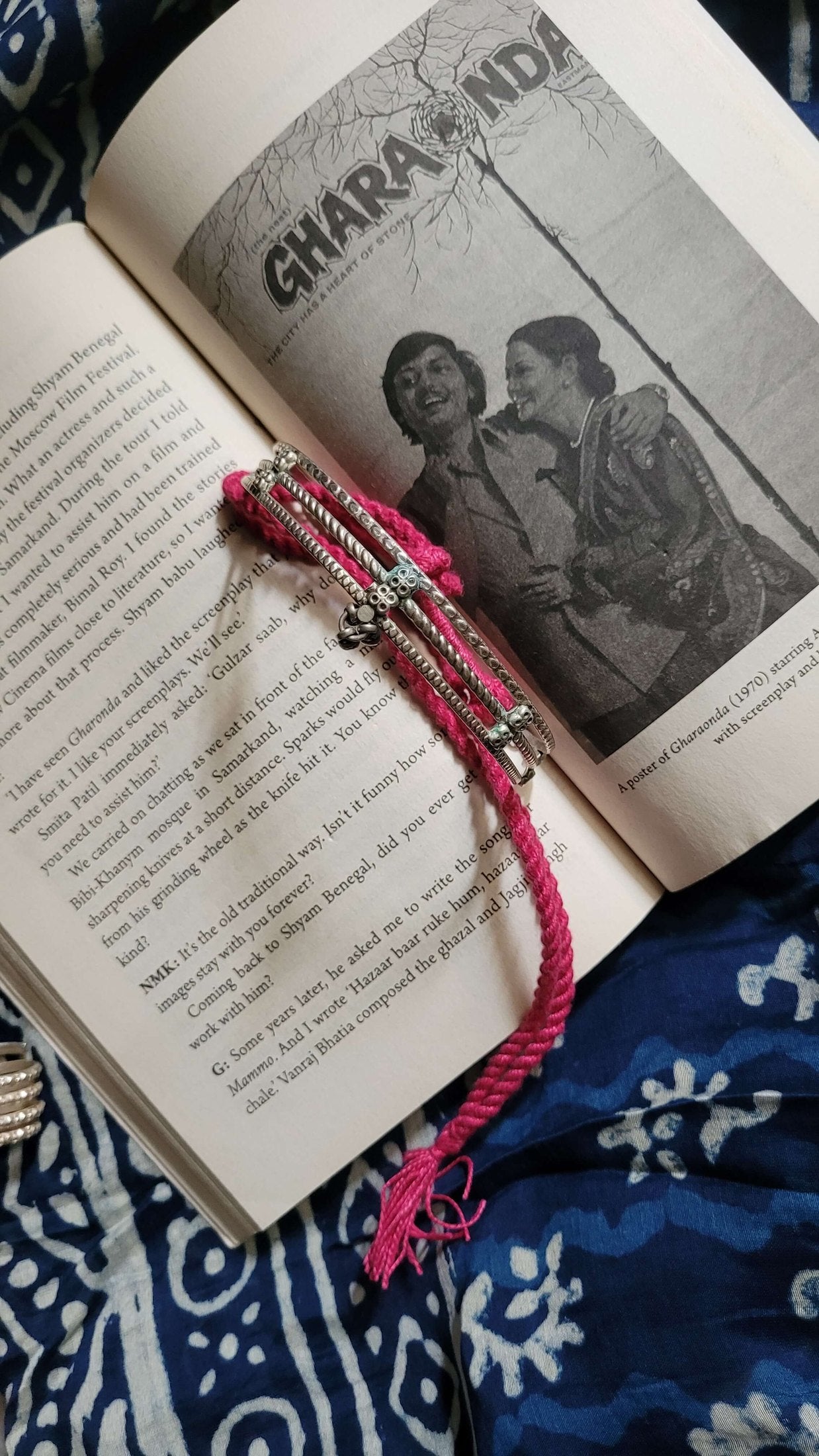 Pink necklace with silver beads on an open book with a black and white photo of two people.