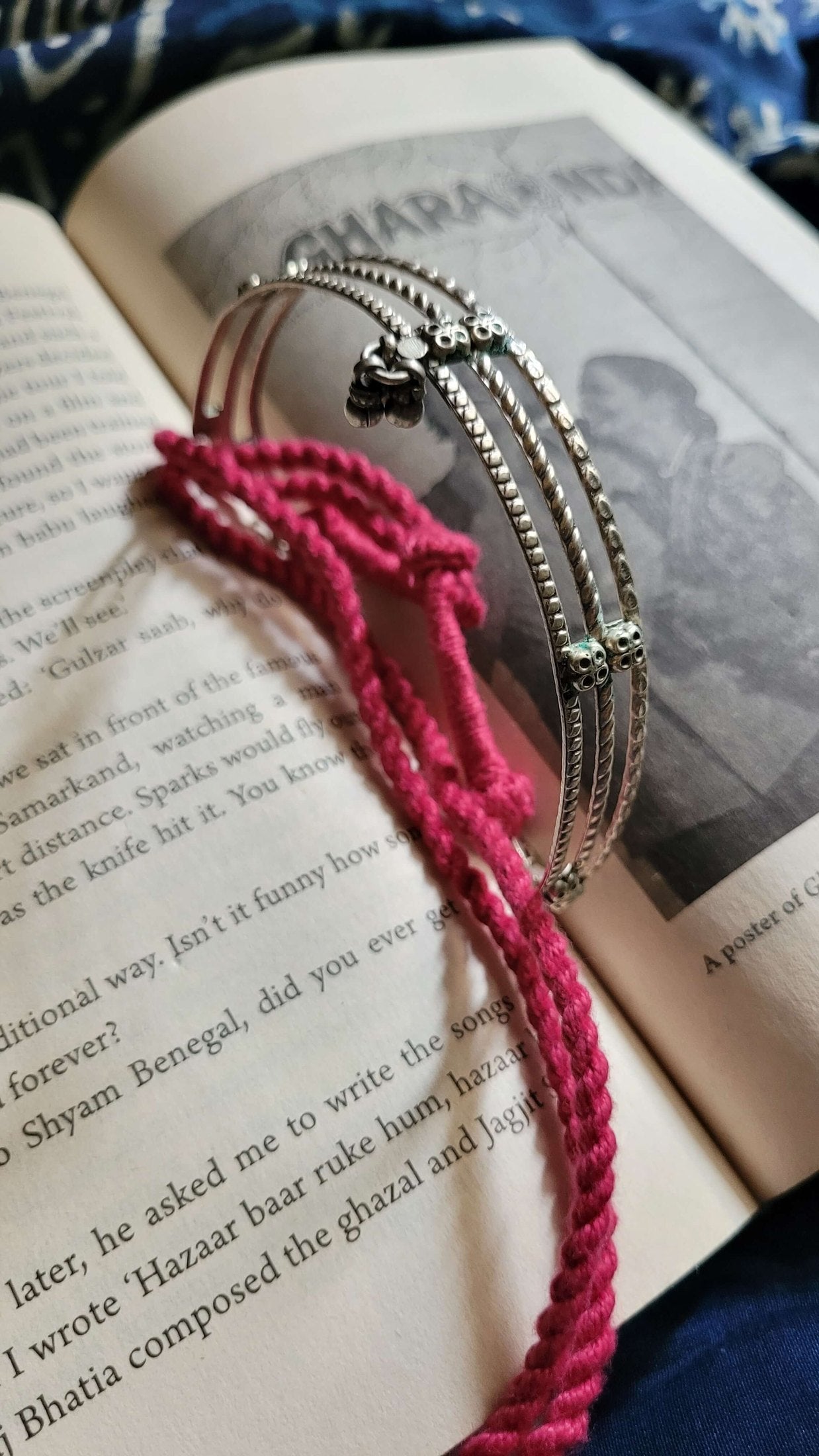 Silver choker with pink cord on an open book