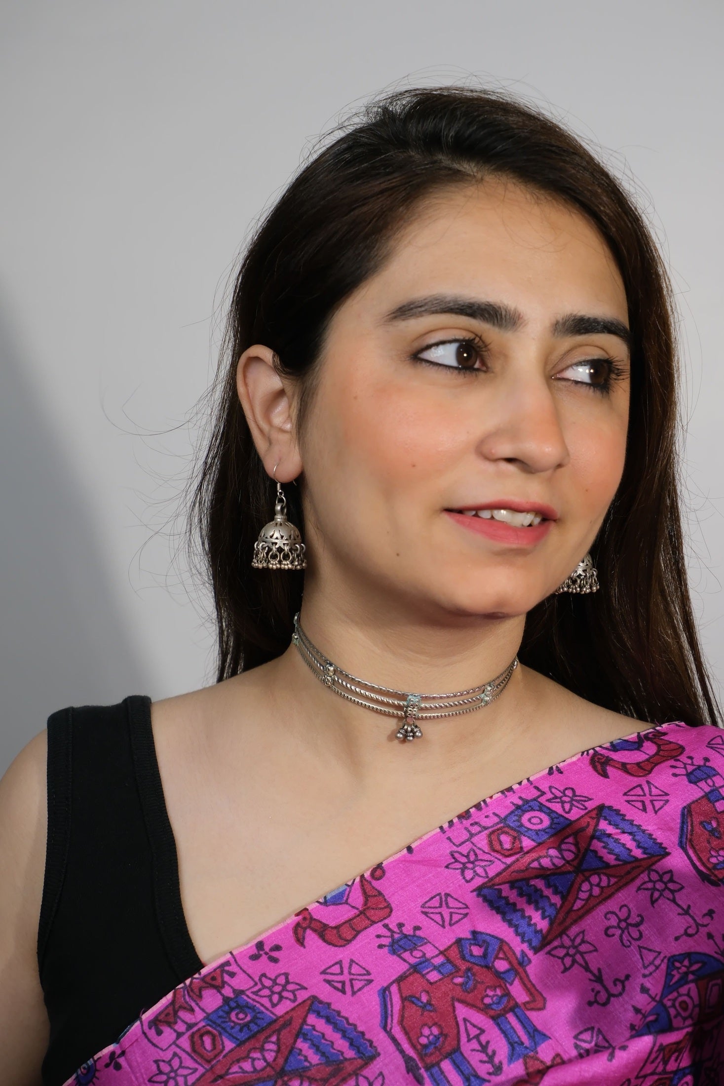 Woman wearing a pink saree with a black blouse against a plain background