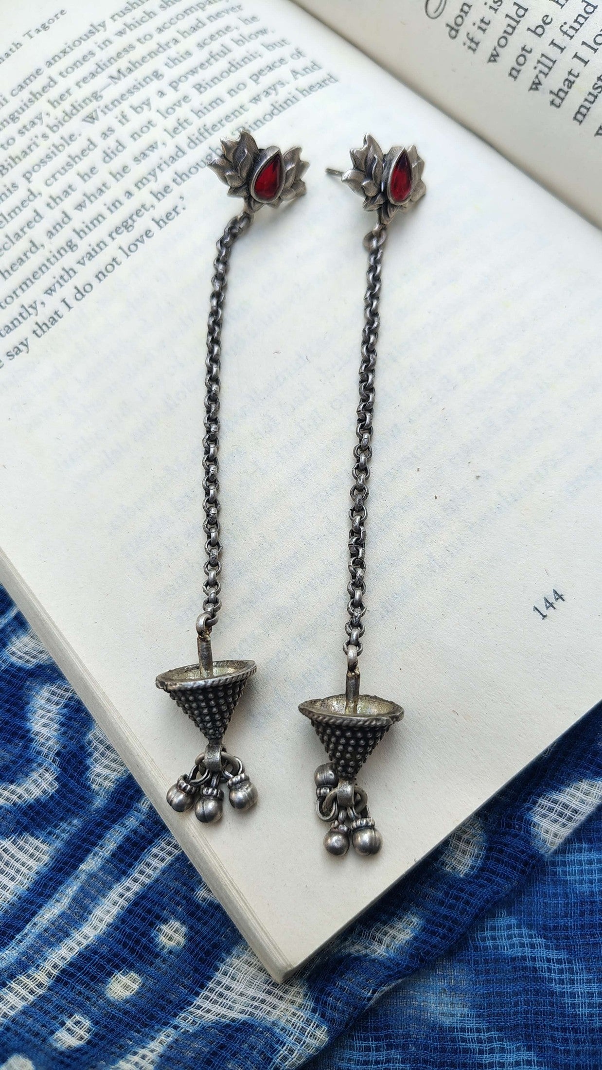 Pair of silver earrings with red stones on an open book