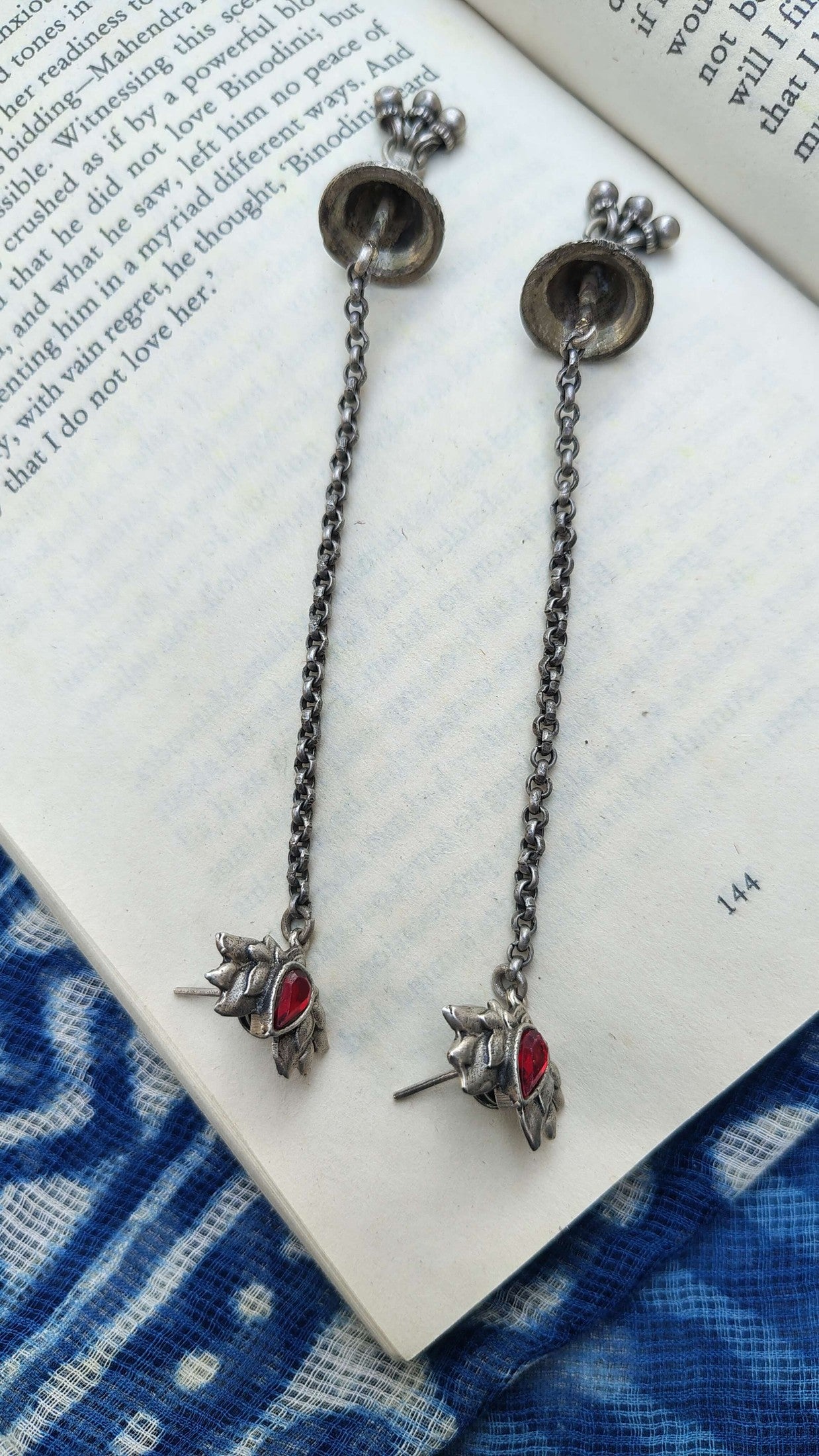 Pair of silver earrings with red stones on a book page