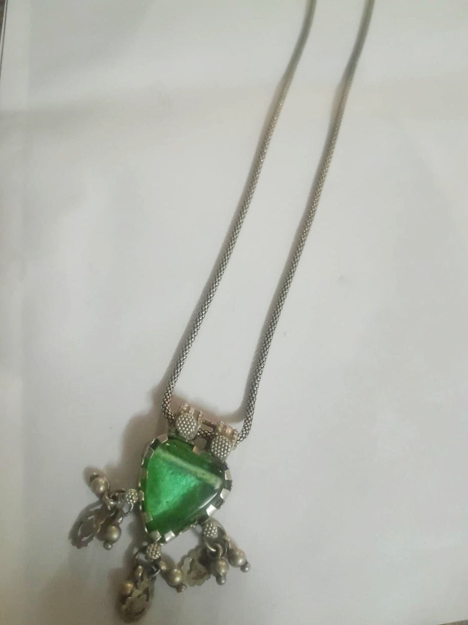 Necklace with a green gemstone pendant on a white background