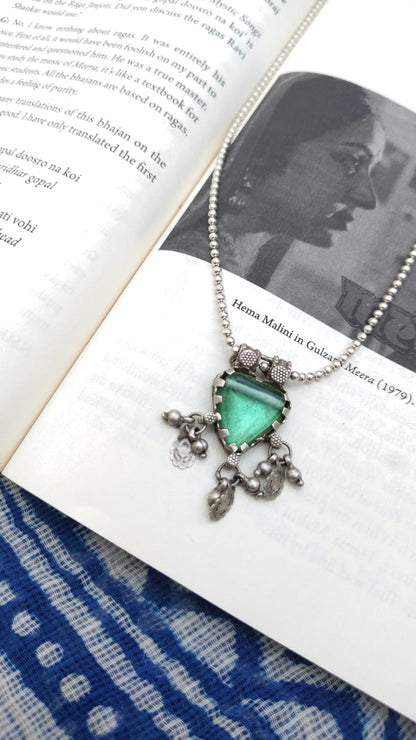 Necklace with a heart-shaped green pendant on an open book