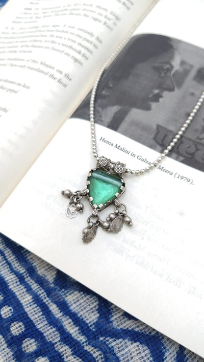 Necklace with a green heart pendant on an open book
