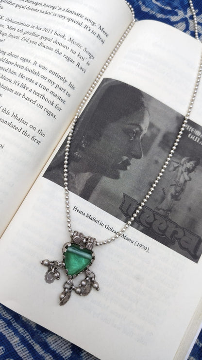 Necklace with a green gemstone pendant on an open book