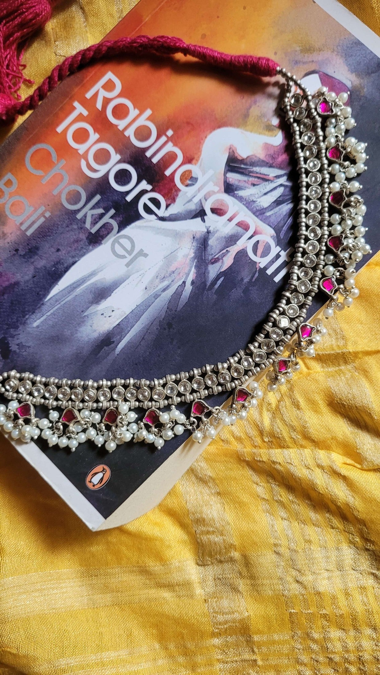 Madhubala Choker Necklace on a book titled 'Rabindranath Tagore' with a yellow fabric background