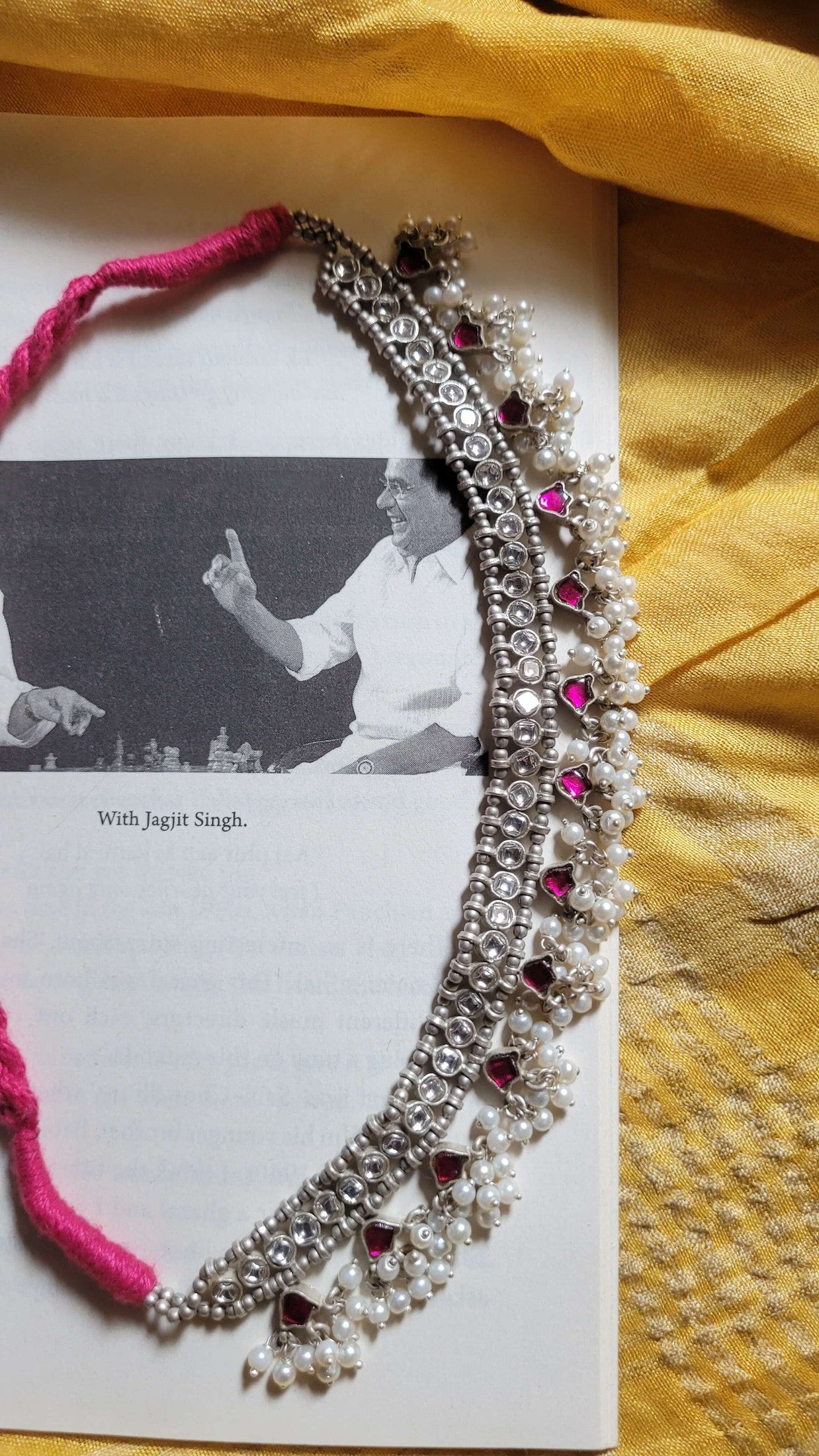 Decorative necklace with pearls and pink stones on a yellow fabric background