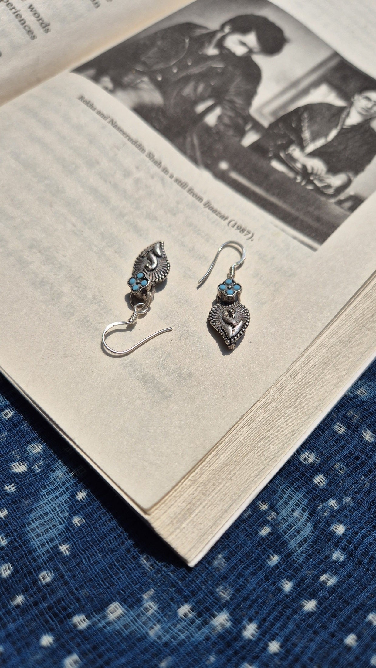 Pair of silver earrings with blue stones on an open book