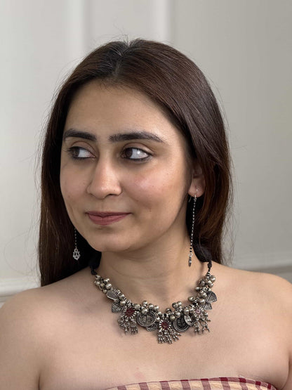 Woman wearing a decorative necklace and earrings against a neutral background