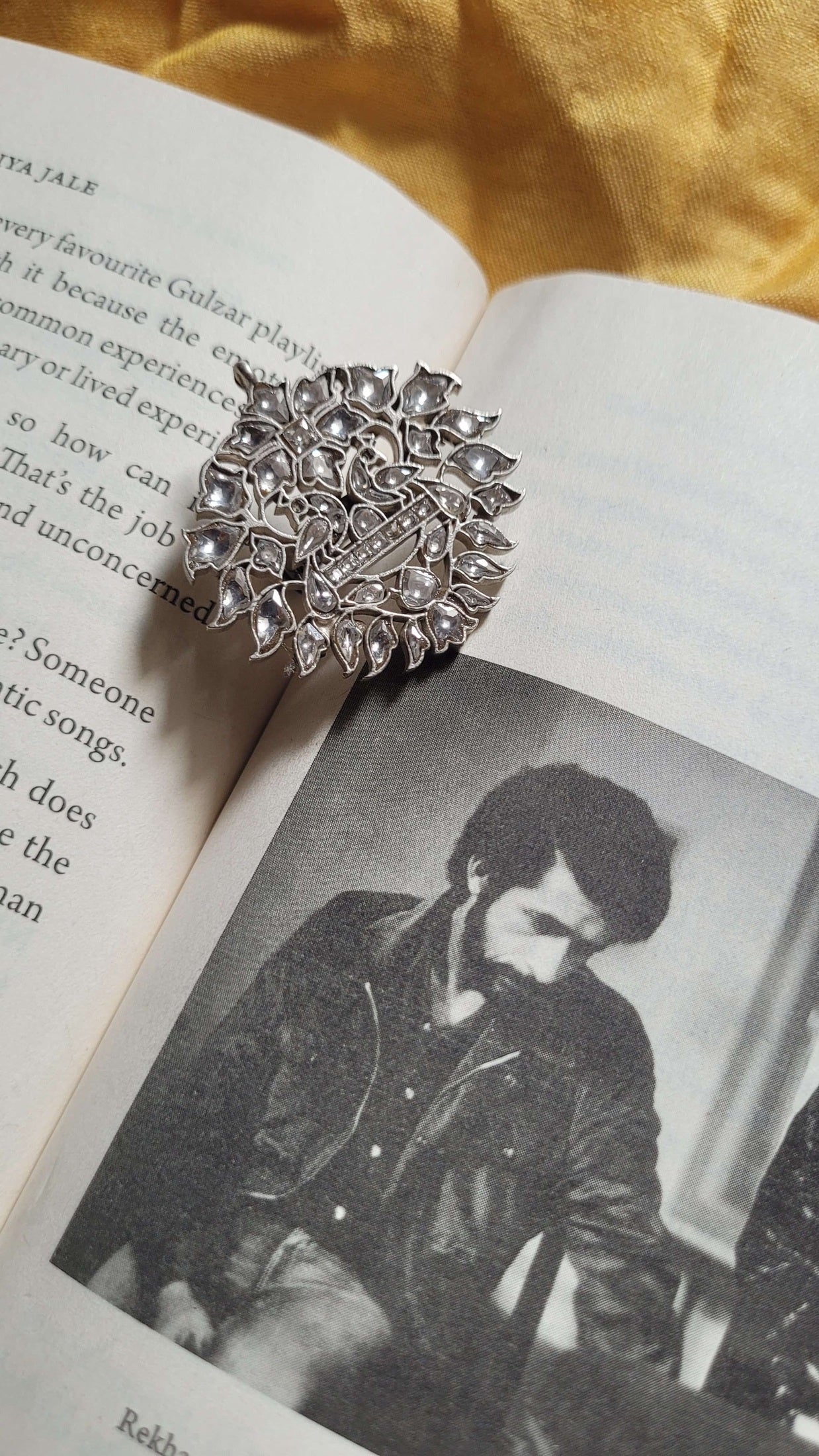 Silver Mythili Ring on an open book with a vintage-style photo in the background