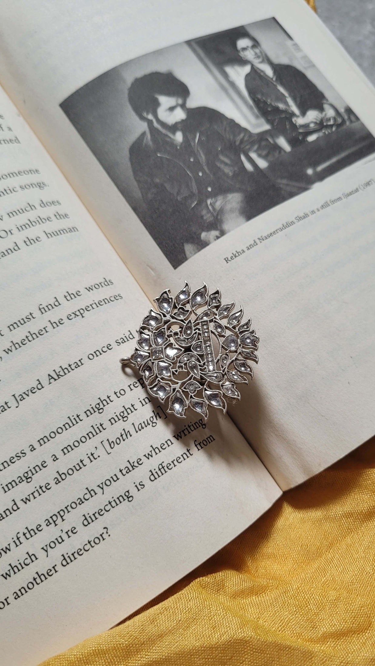 Pure silver kundan ring on an open book with a yellow fabric background