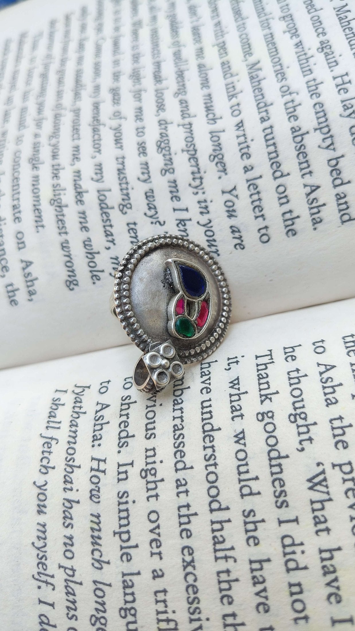 Pure silver ring with colorful stones on an open book