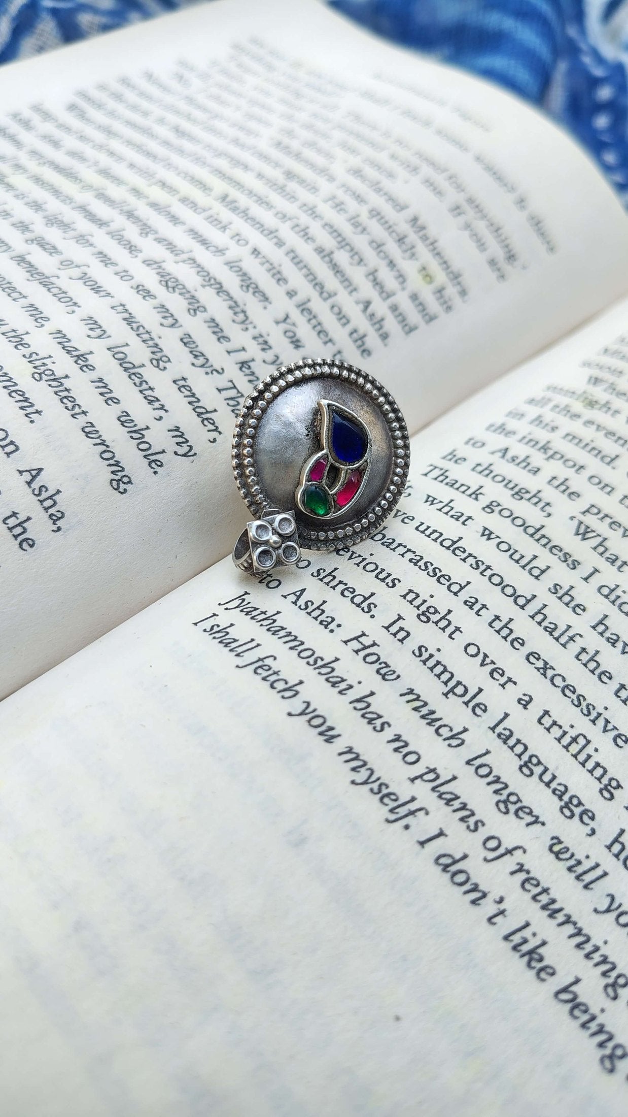 Pure silver ring with colorful kundan stones on an open book