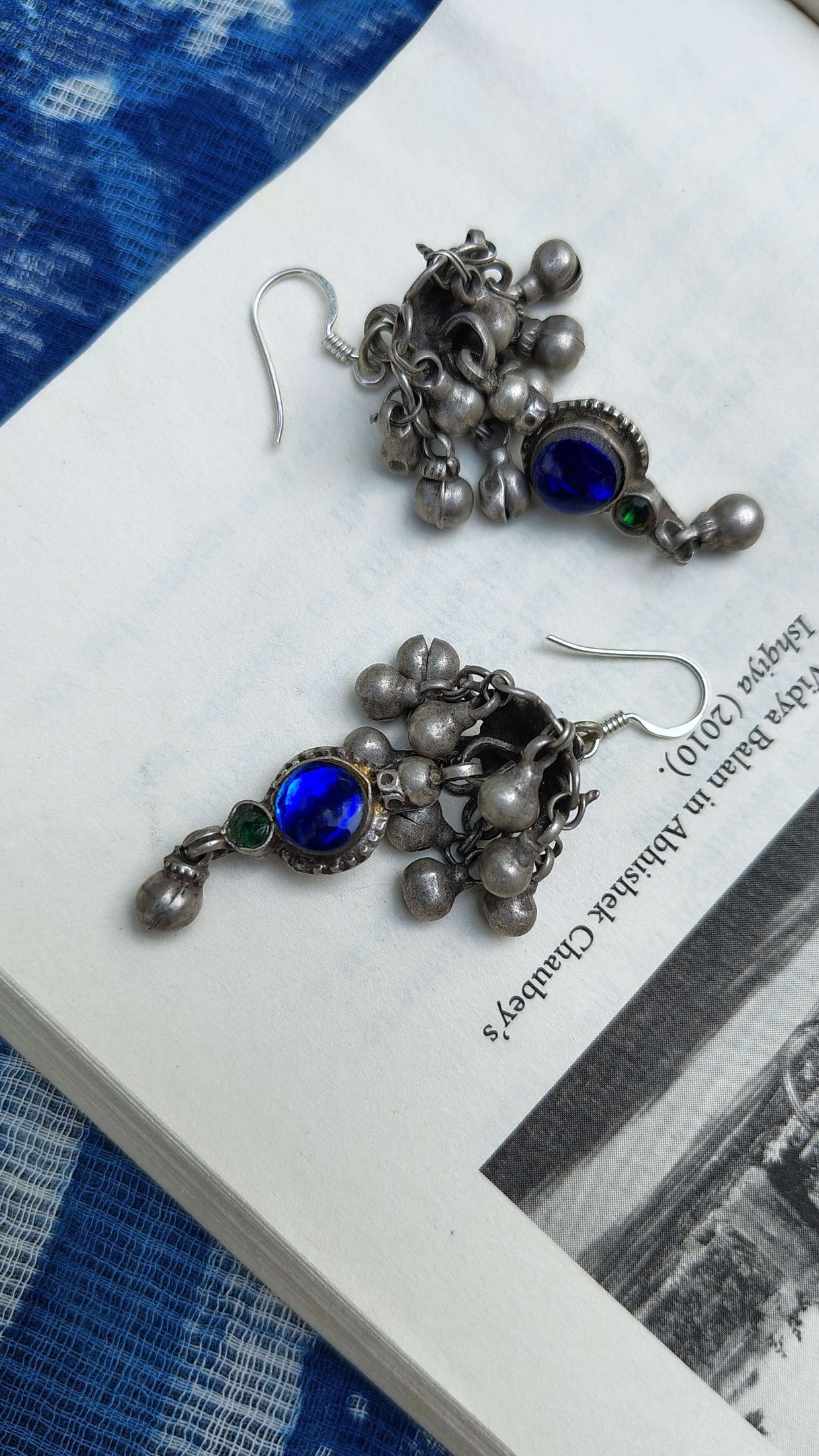Pair of silver earrings with blue gemstones on a book