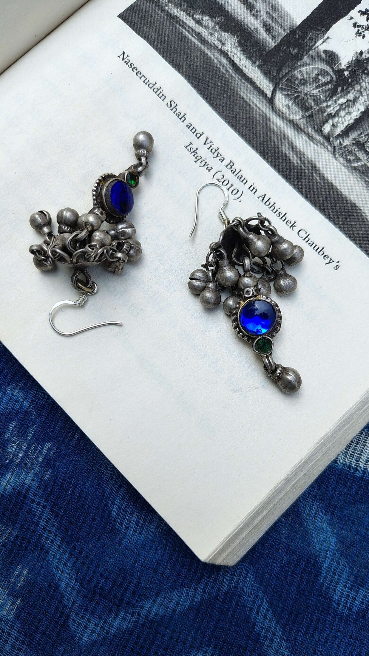 Pair of silver earrings with blue stones on a book