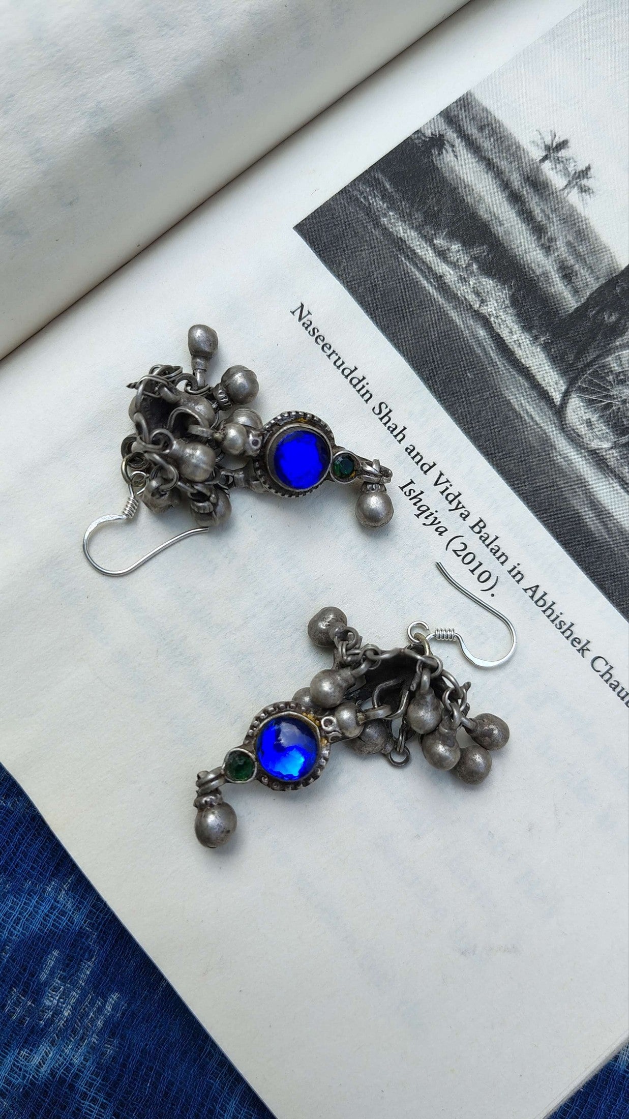 Pair of silver earrings with blue gemstones on a book