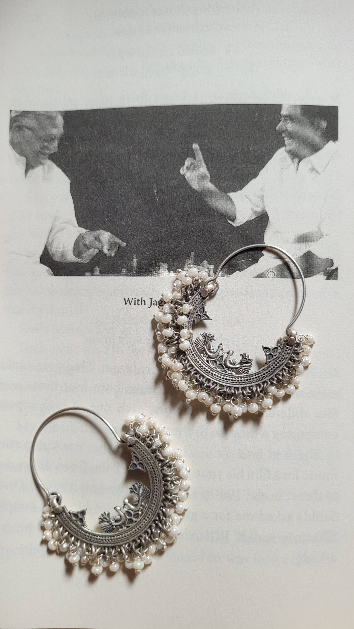 Ornate silver hoop earrings with pearl-like beads on a light background.
