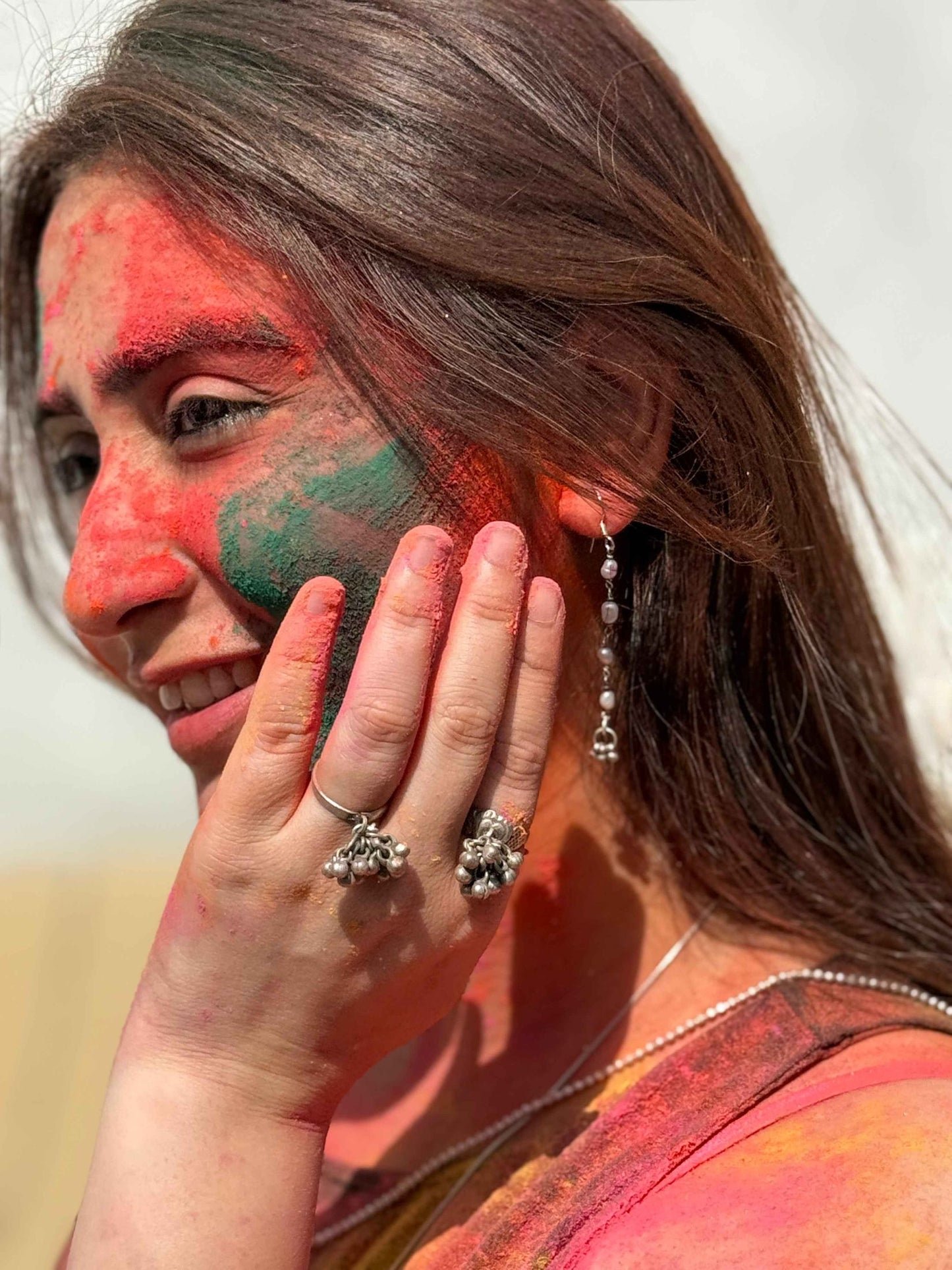 Woman with colorful face paint and silver rings, possibly celebrating Holi festival.