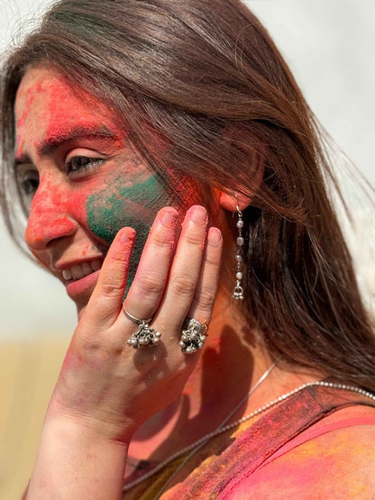 Woman with colorful face paint and silver rings, possibly celebrating Holi festival.