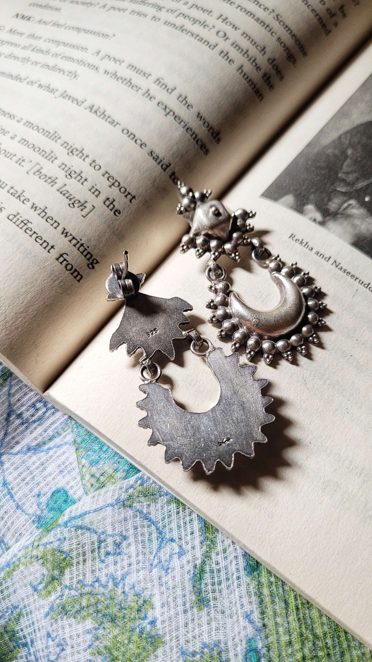 Pair of silver earrings on an open book.