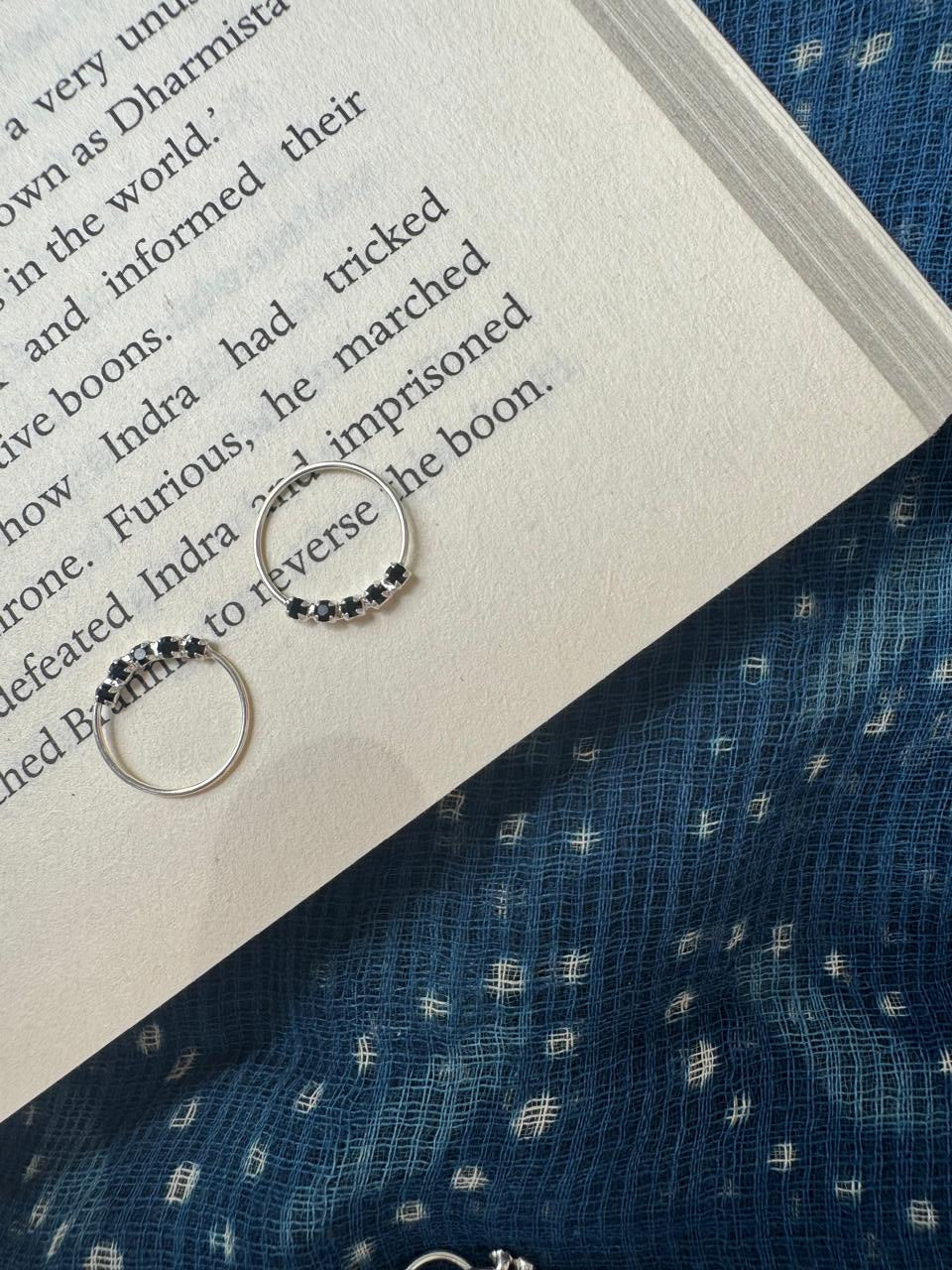 Two silver hoops with beaded designs on an open book.