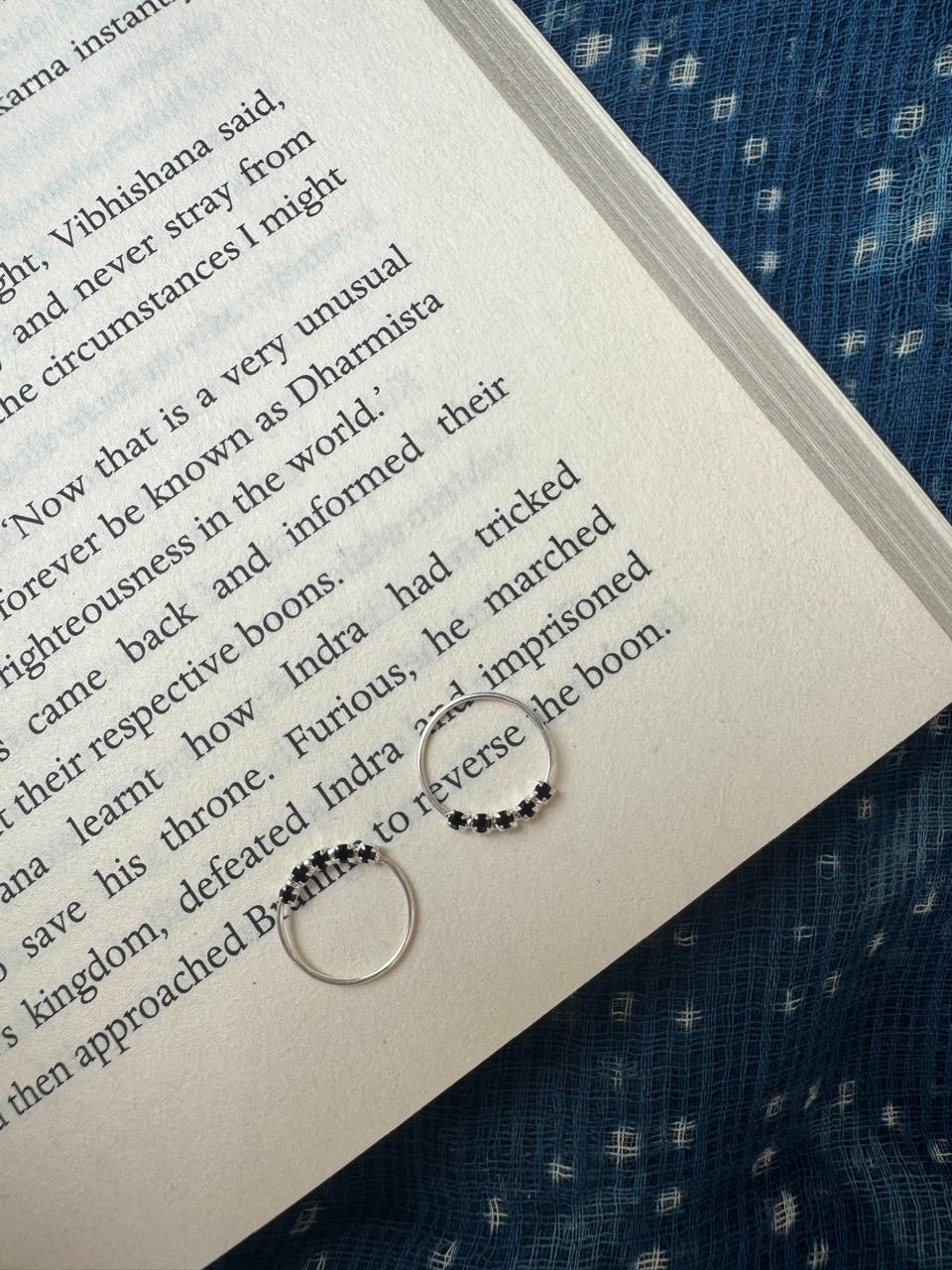 Two silver hoops with blackgemstones on an open book