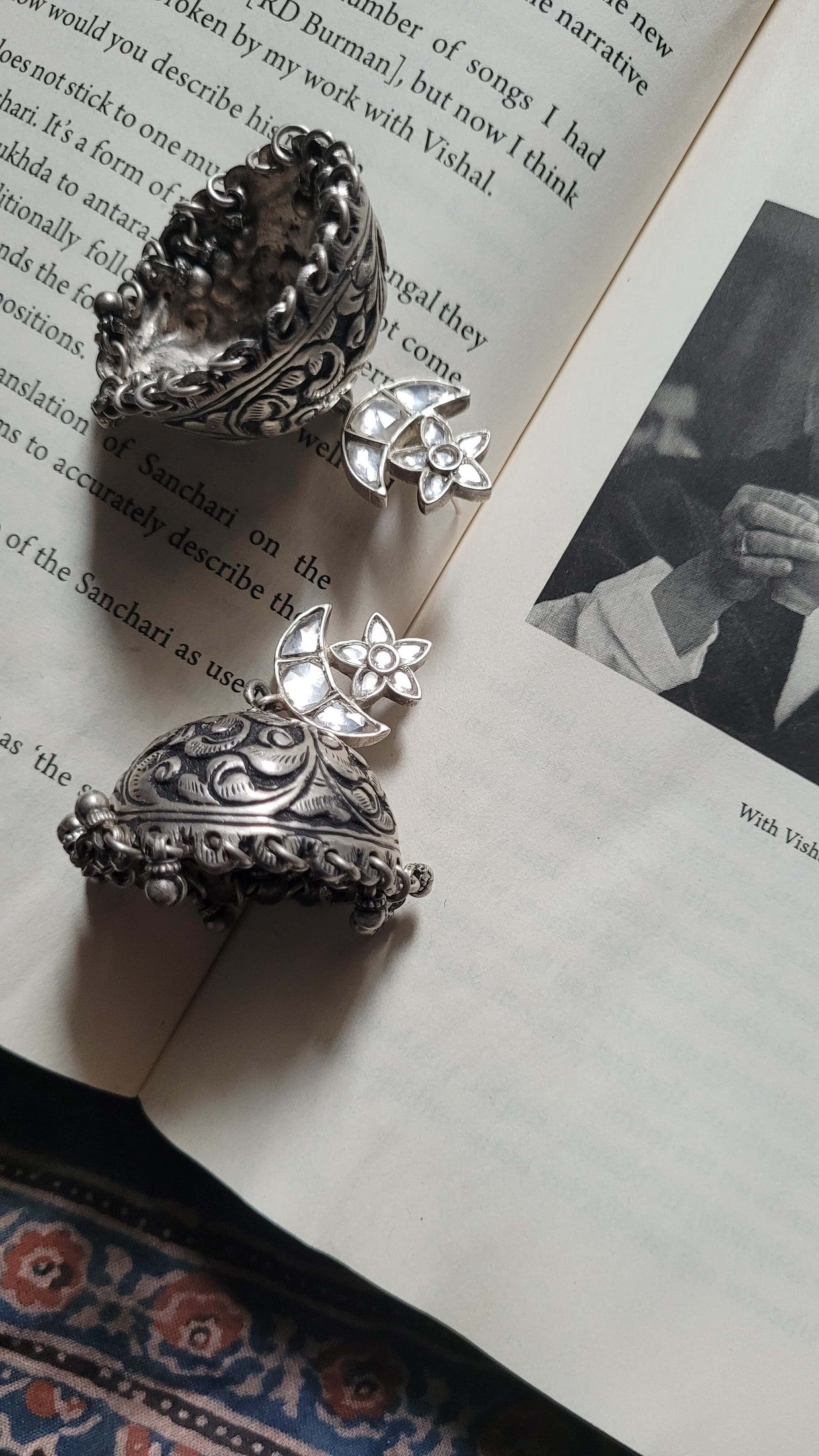 Silver earrings on an open book with a black and white photo underneath