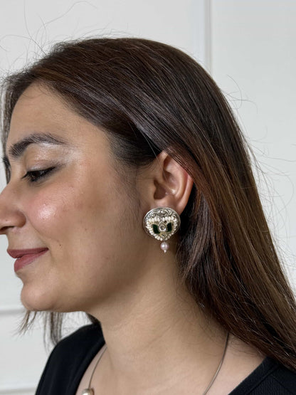 Woman wearing a pure silver kundan earring with lotus motif in green against a white background