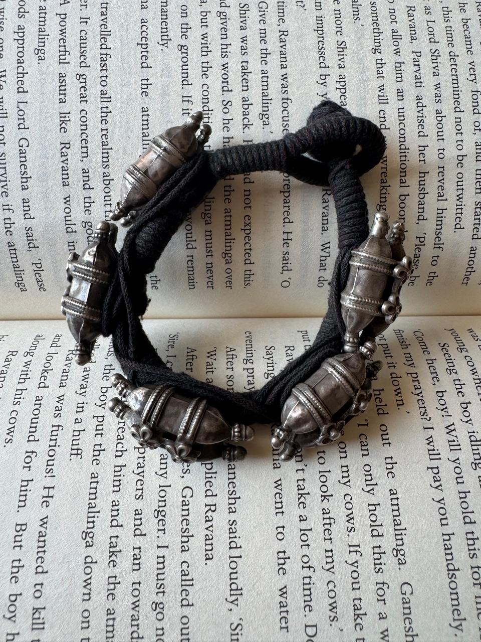 Black braided bracelet with silver beads on an open book