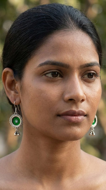 Woman wearing green earrings with a blurred natural background