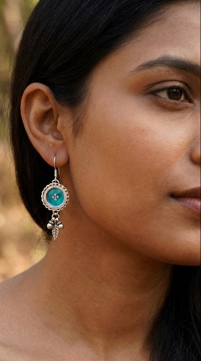 Close-up of a woman wearing a turquoise earring with a blurred natural background