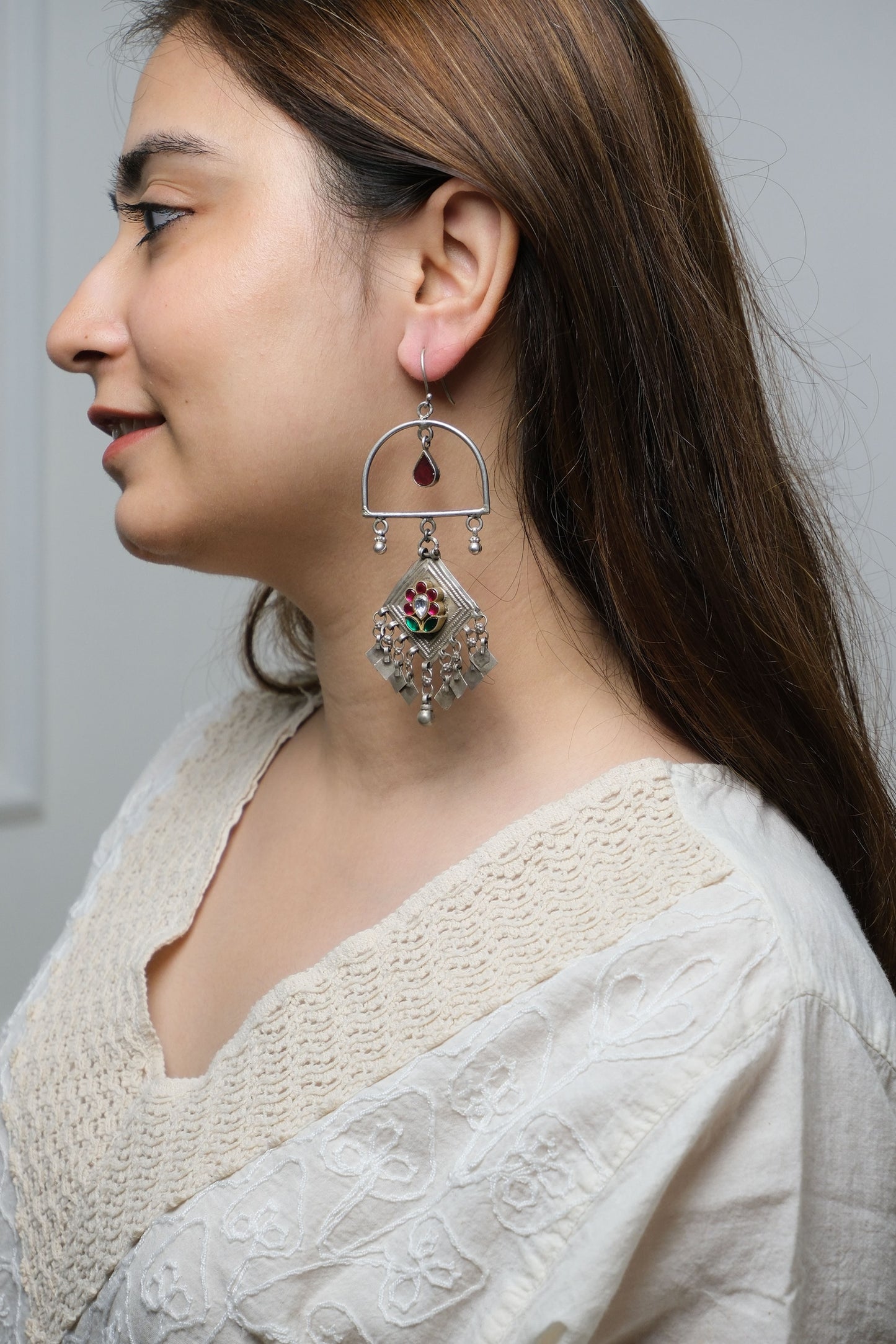 Woman wearing a decorative earring with a white lace garment.
